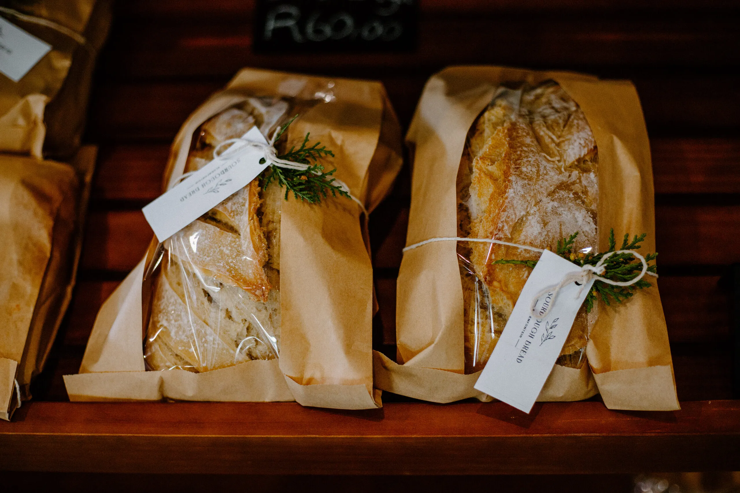 Freshly baked loaves wrapped in paper on a wooden shelf