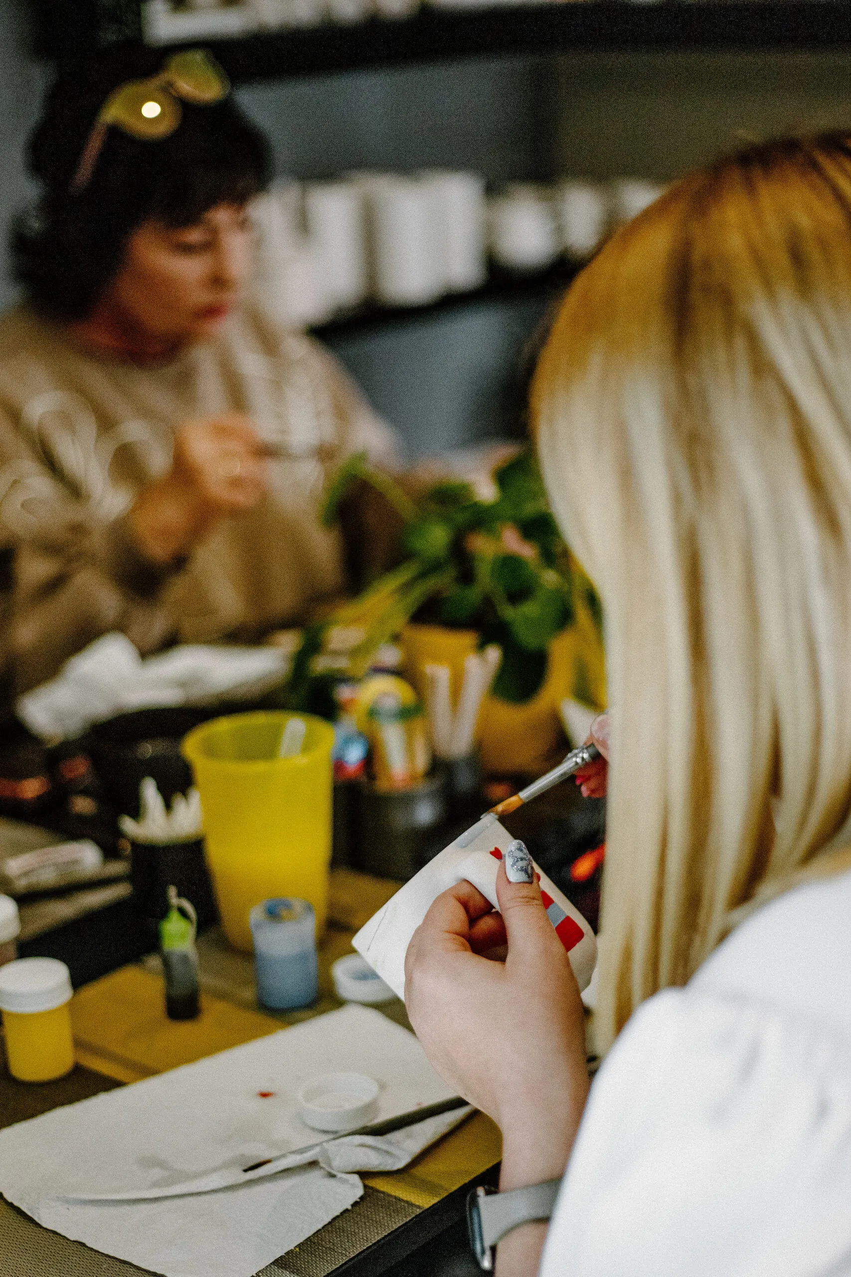 Two people painting ceramic pieces together at a table